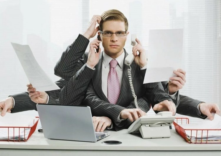 A stressed professional multitasking in an office, surrounded by work materials.